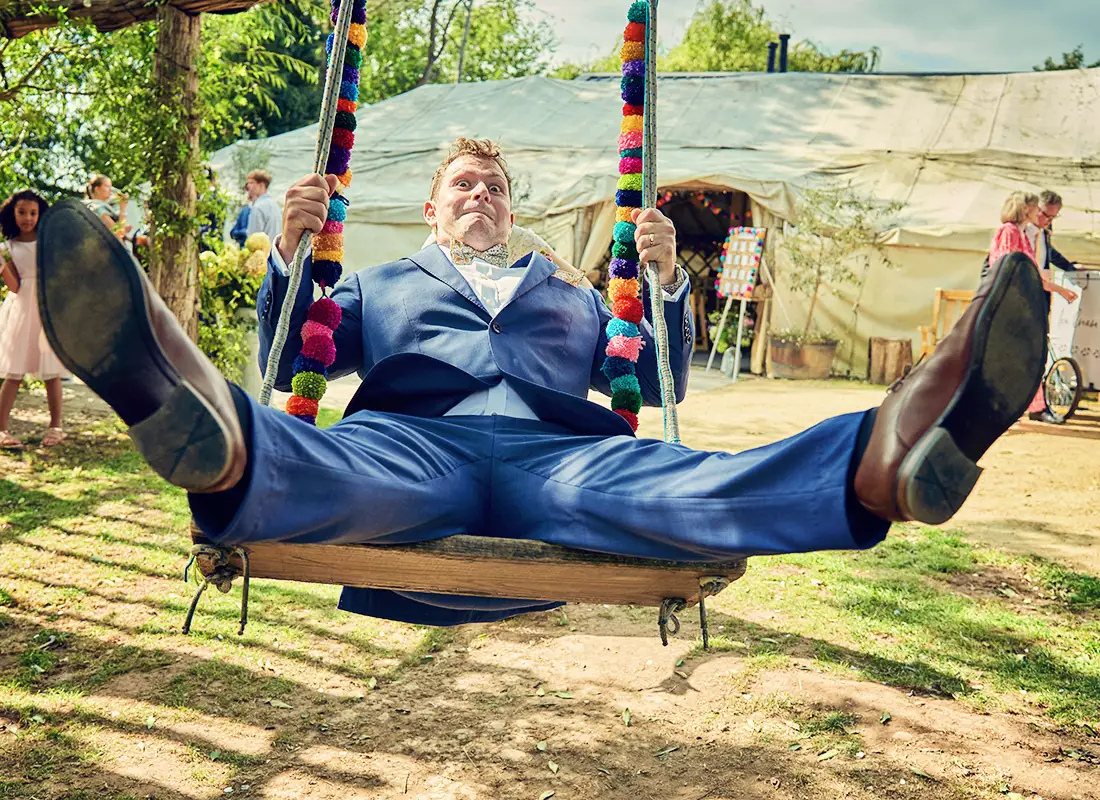 Groom on a swing at a glamping wedding