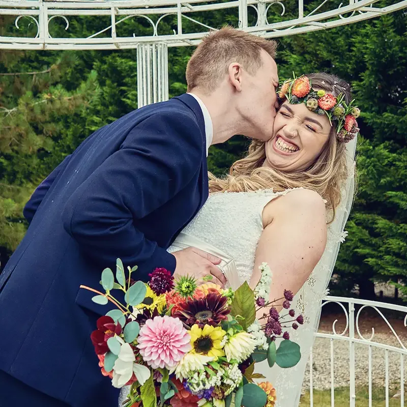 Groom kissing bride on cheek after their wedding in Worcester