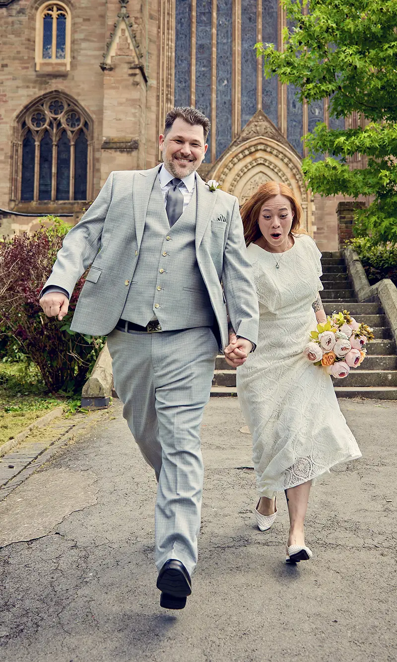 Happy couple running down steps in front of Droitwich Spa church Happy couple running down steps in front of Droitwich Spa church