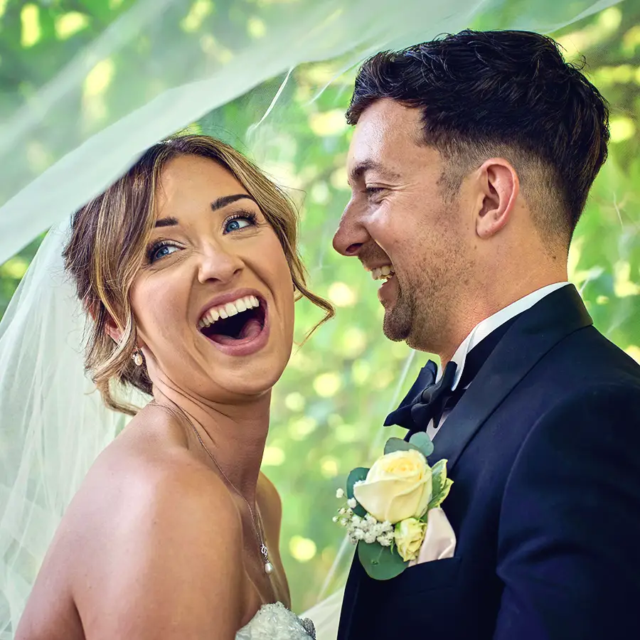 Bride and groom laughing together under the veil
