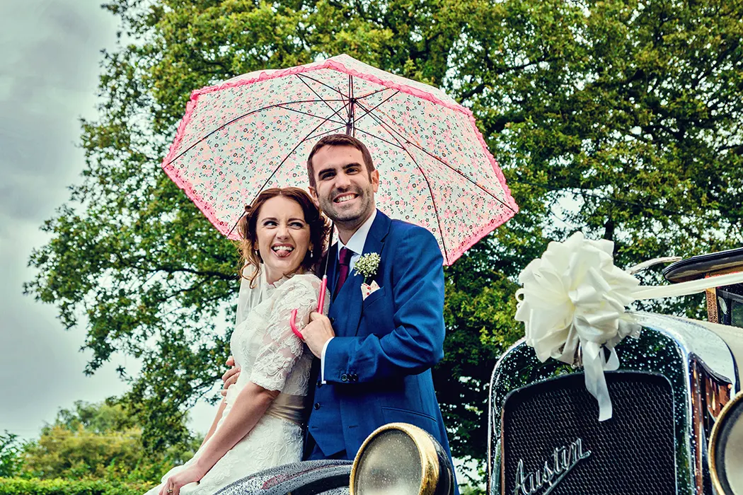 Bride and groom lauging outside in the rain outside Bentley Village Hall Bride and groom lauging outside in the rain outside Bentley Village Hall