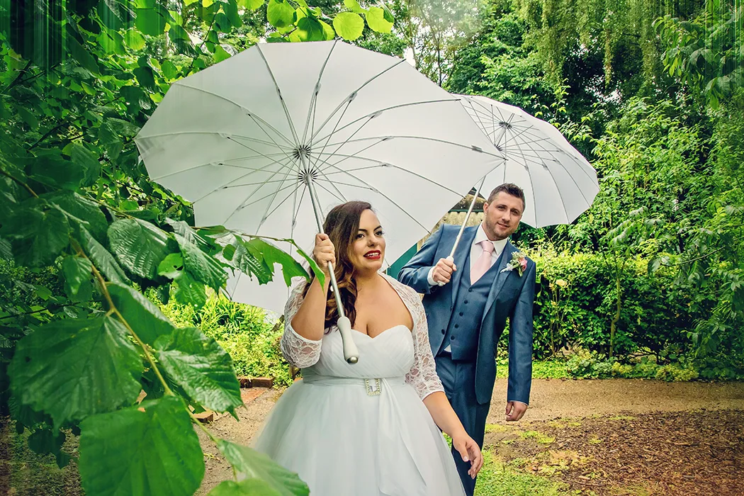 Newlyweds in the pouring rain with umbrellas at Avoncroft Museum