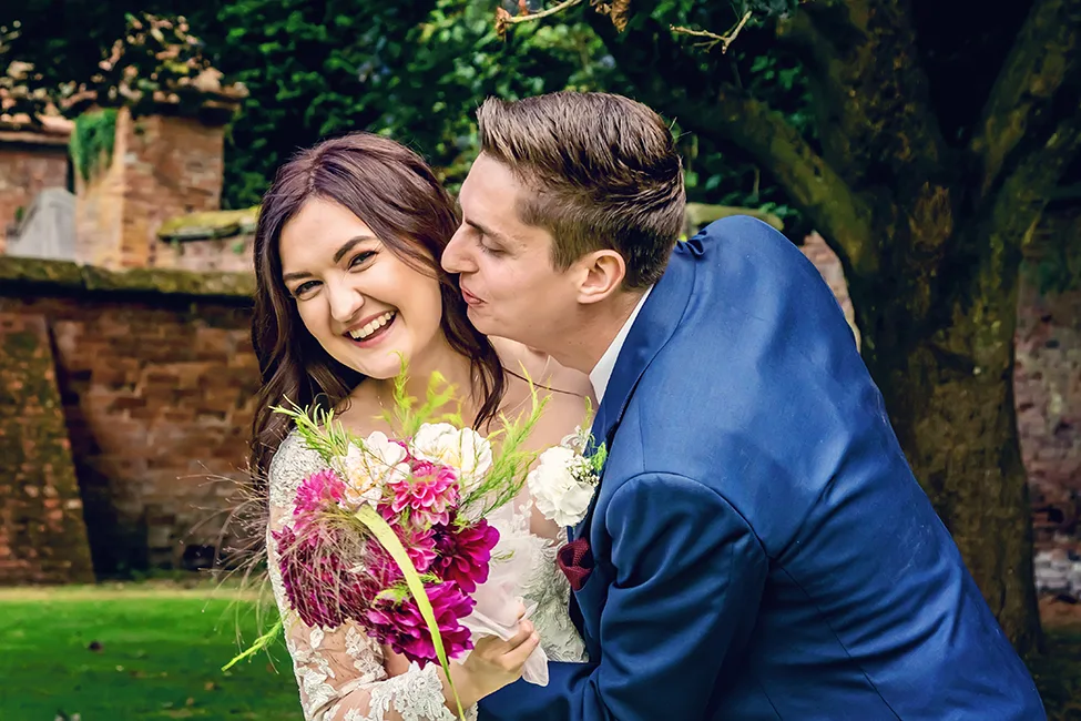 Groom trying to steal a kiss from the bride at Gorcott Hall